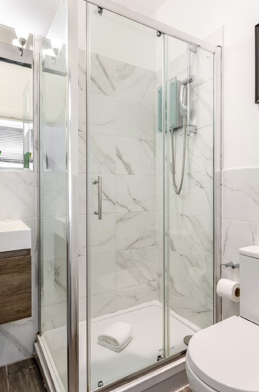 Modern bathroom with marble shower enclosure, toilet, and white sink vanity