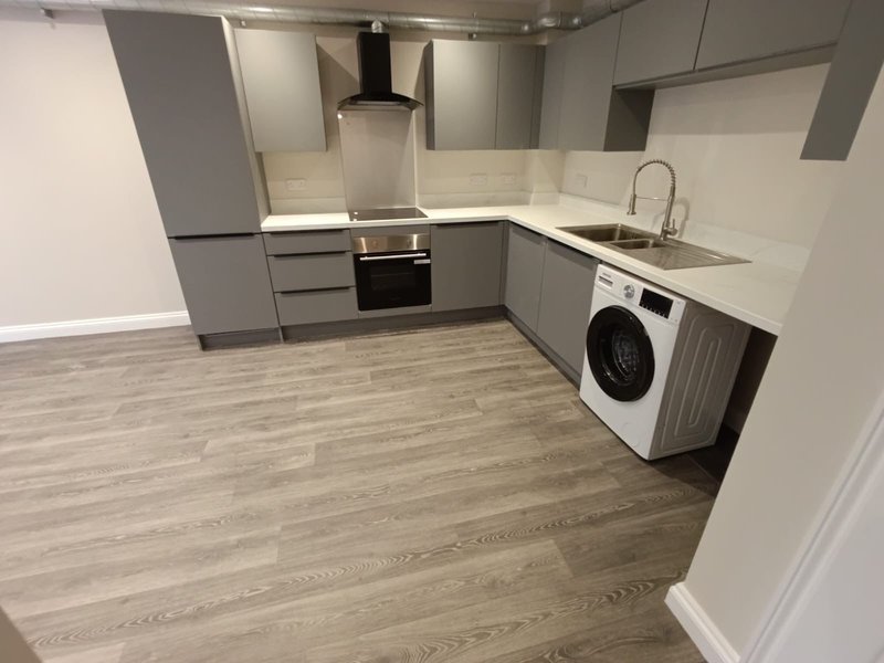 Modern kitchen with gray cabinetry, white countertops, integrated appliances, and wood-effect flooring
