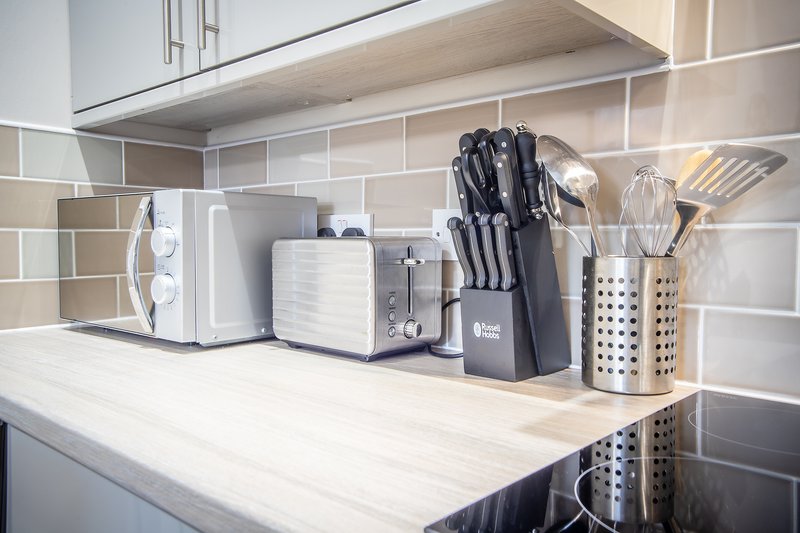 Modern kitchen counter with appliances, knife block, utensils and white subway tile backsplash