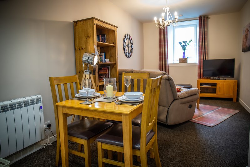 Open-plan living and dining area with wooden furniture, set table, and window view