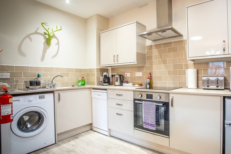 Modern kitchen with cream cabinetry, tiled backsplash, integrated appliances and washing machine