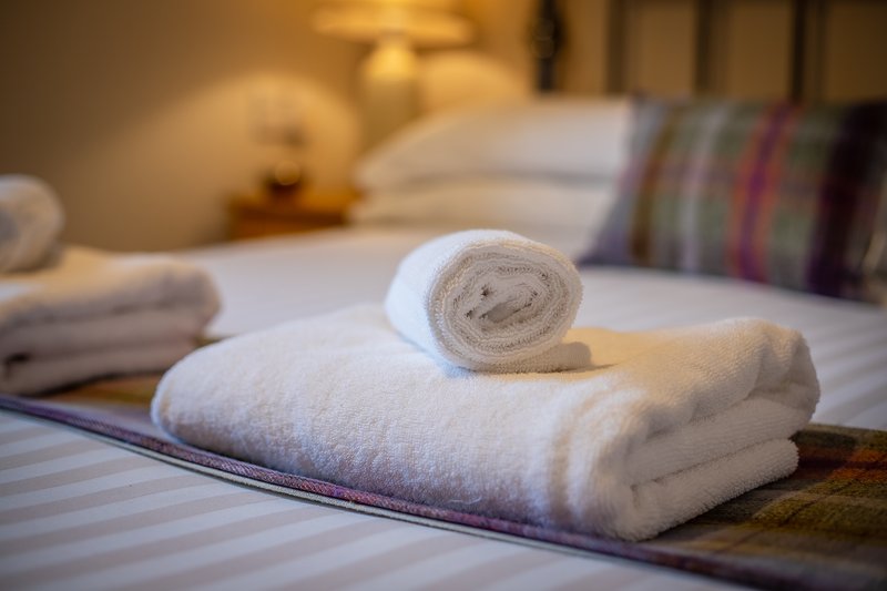Bedroom with rolled white towels on striped bedding and pillows in background
