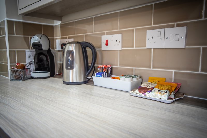 Kitchen countertop with coffee maker, kettle, electrical outlets and hospitality items