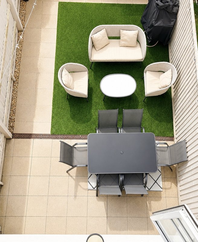 Overhead view of garden patio with seating areas, dining table, artificial grass and paved surround