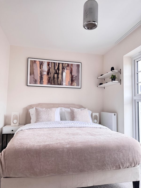 Modern bedroom with double bed, framed wall art, bedside tables and ceiling light fixture