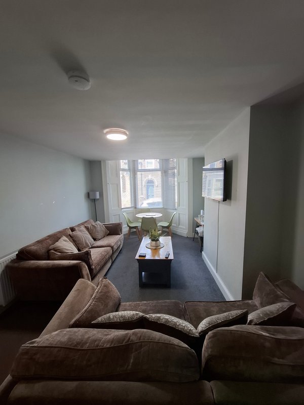 Modern living room with brown sectional sofa, coffee table, windows, and recessed ceiling lights