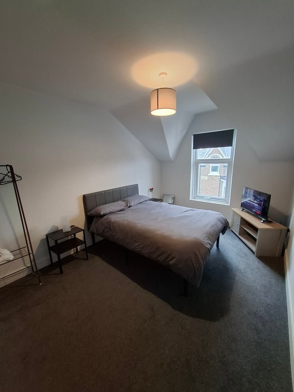 Modern bedroom with double bed, pendant ceiling light, window and small desk area