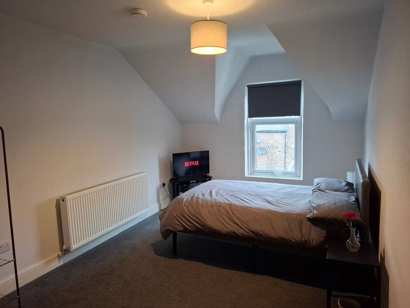 Attic bedroom with double bed, TV, ceiling light, radiator and skylight window