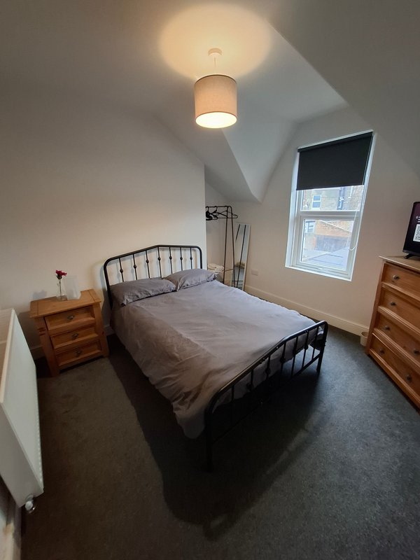 Bedroom with double bed, wooden nightstands, ceiling light, and window with blinds