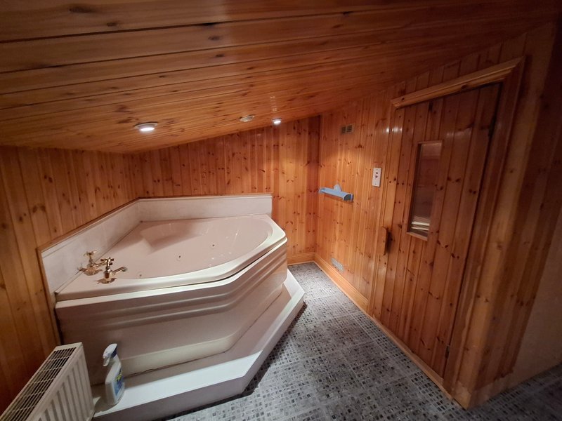 Wooden bathroom with large corner bathtub, tile floor, and recessed lighting