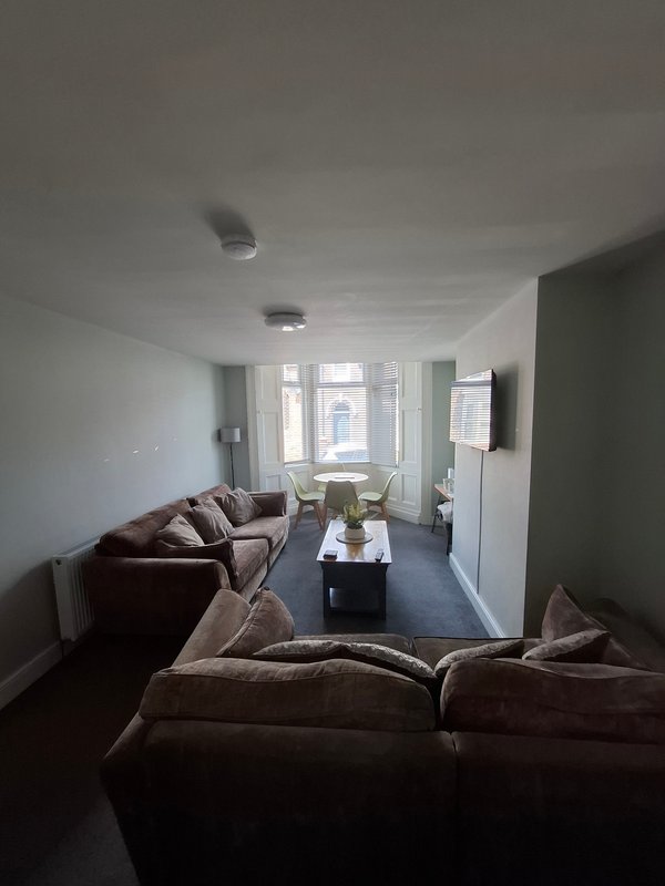 Living room with brown sofas, coffee table, large windows and blue carpet