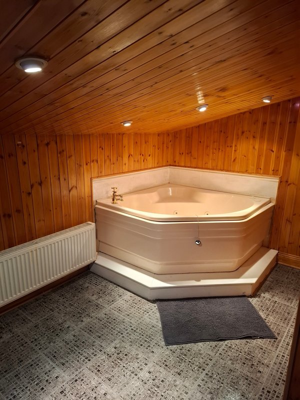 Spa room with corner hot tub, wooden walls, recessed lighting and tile flooring