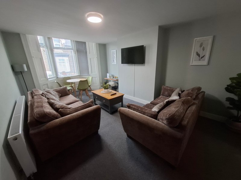 Living room with two brown sofas, TV on wall, wooden coffee table, and large windows