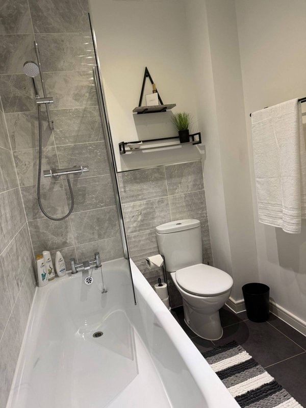 Modern bathroom with bathtub, shower, toilet, and gray tile walls