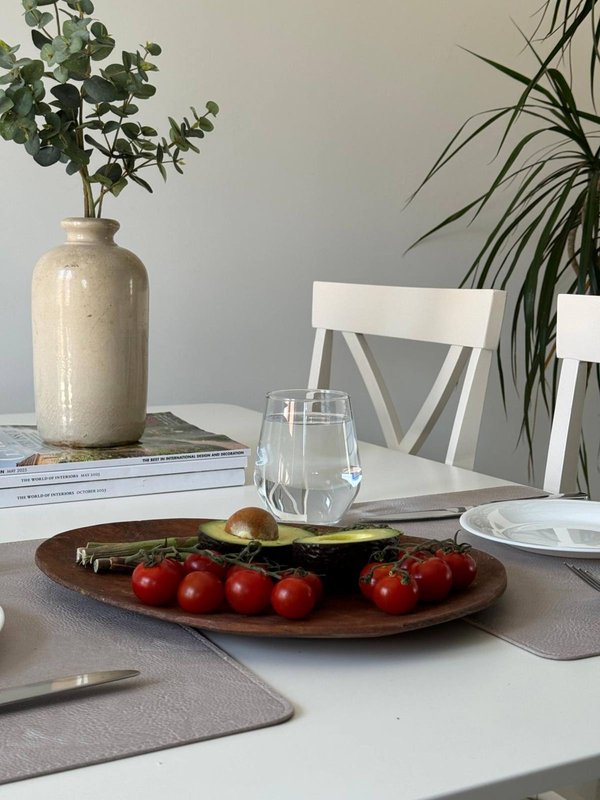 Dining table with fresh vegetables, glasses, plants and white chairs