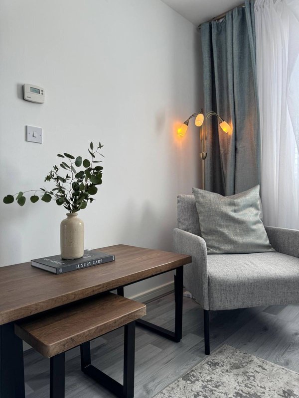 Modern seating area with grey armchair, wooden table, potted plant and warm lighting