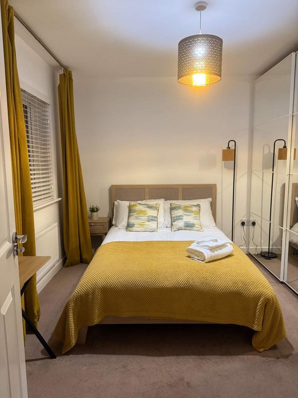 Bedroom with double bed, yellow bedding, pendant light, and built-in wardrobes