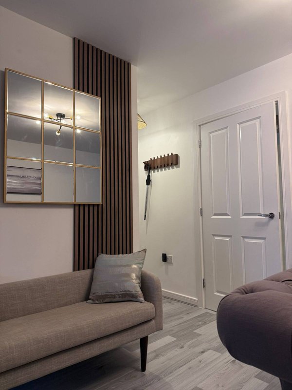 Modern bedroom with gray sofa, mirrored wall panel, curtains, and white closet doors