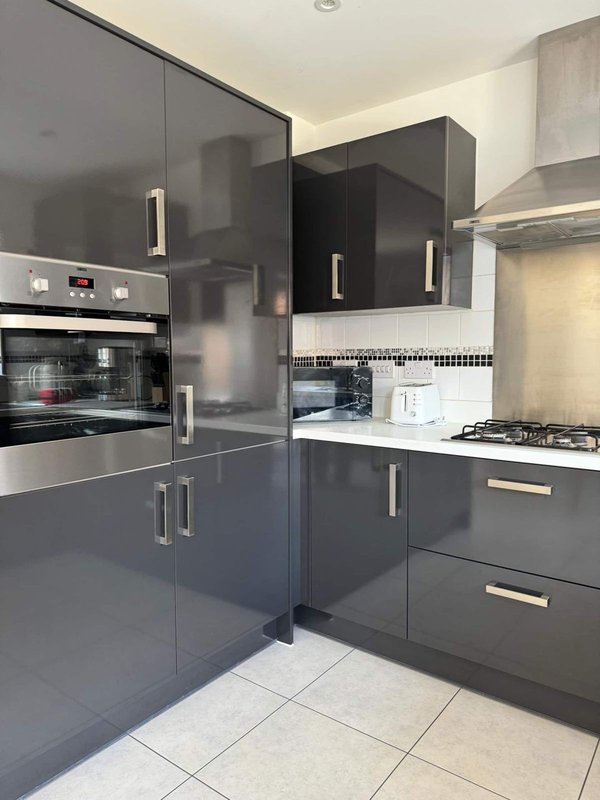 Modern kitchen with dark grey cabinetry, stainless steel appliances, gas hob and tiled flooring