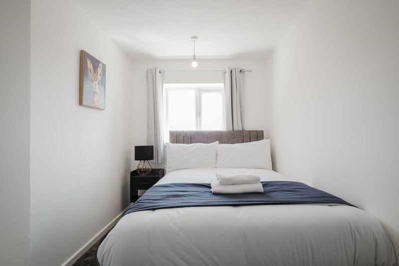 Bright modern bedroom with double bed, blue bedding, white pillows and small bedside table