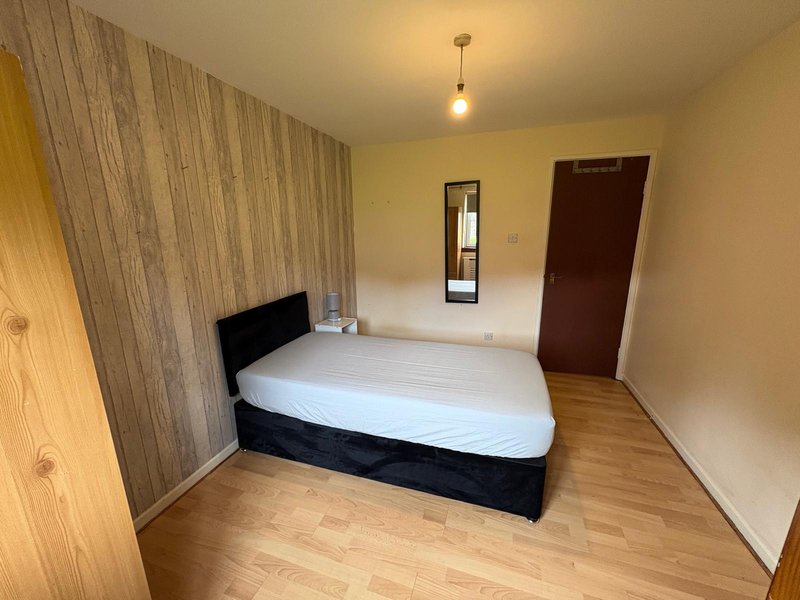Bedroom with double bed, wood-paneled accent wall, wooden flooring and pendant light