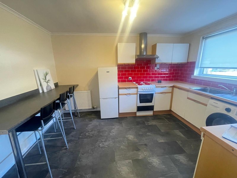 Modern kitchen with red tile backsplash, white appliances, breakfast bar seating and window view