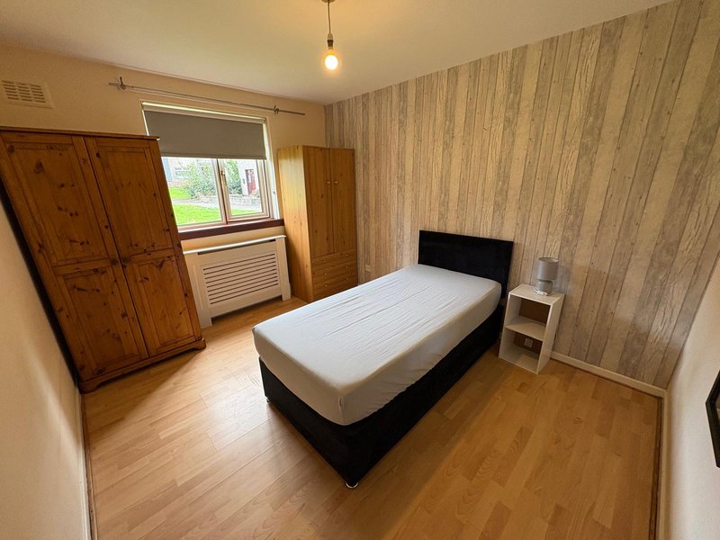 Bedroom with single bed, wooden wardrobe, wooden floor and striped wallpaper