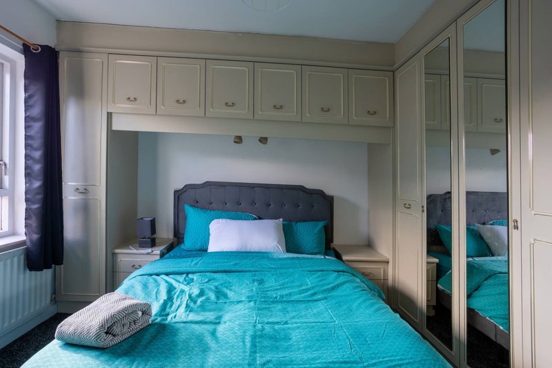 Bedroom with turquoise bedding, built-in wardrobe, and mirrored doors