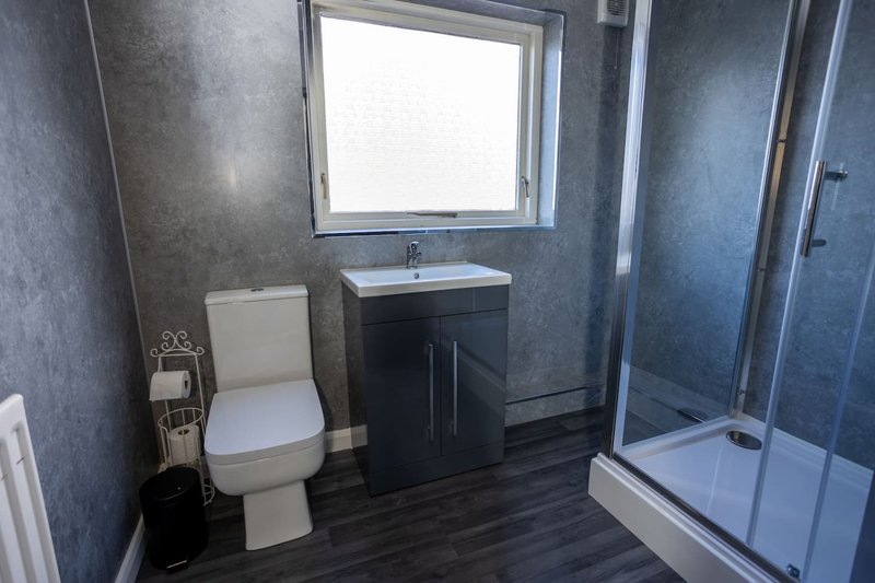 Modern bathroom with toilet, black vanity unit, sink, shower enclosure and window