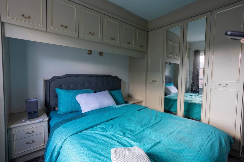 Bedroom with double bed, turquoise bedding, built-in wardrobes and mirrored sliding doors