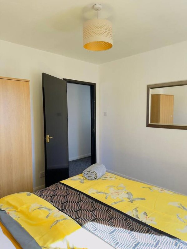 Bedroom with two single beds with yellow bedding, wooden doors, pendant light and mirror
