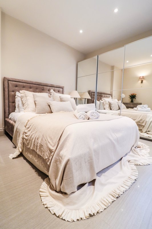 Modern bedroom with double bed, mirrored wardrobe, neutral bedding and recessed ceiling lights