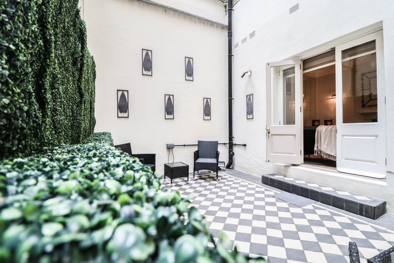 Modern courtyard patio with checkered flooring, seating area, climbing ivy and French doors
