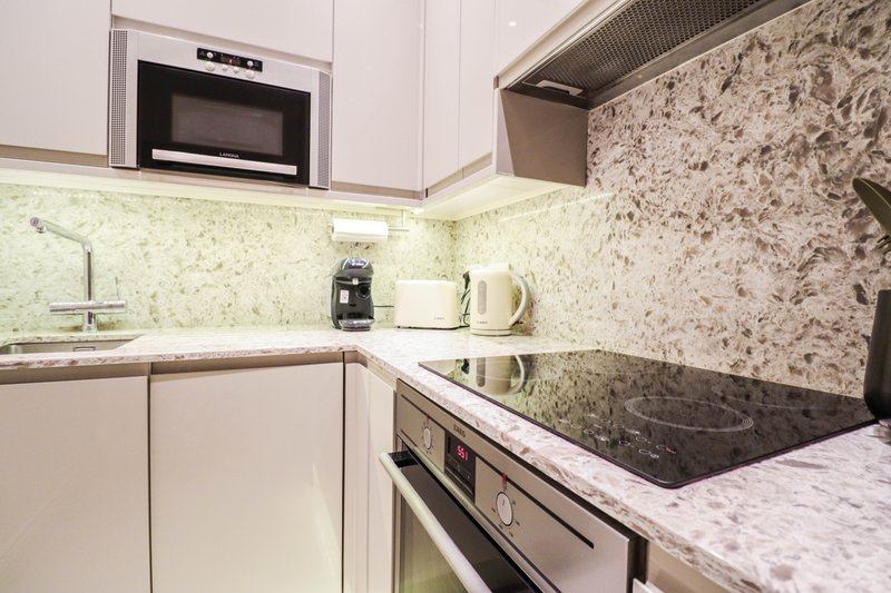 Modern kitchen with white cabinets, marble countertops, stainless steel appliances and backsplash