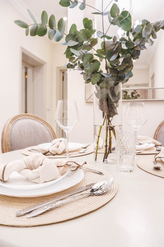 Minimalist dining table with place settings, eucalyptus floral arrangement and glassware