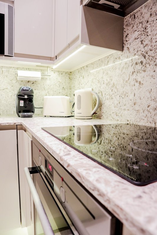 Modern kitchen with white cabinetry, marble countertop, and stainless steel appliances