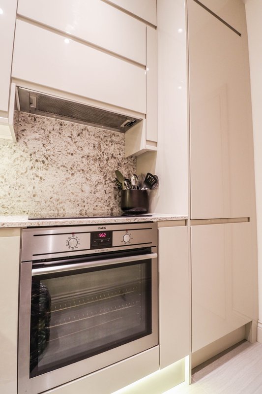 Modern kitchen with cream cabinets, granite backsplash, stainless steel oven and range hood
