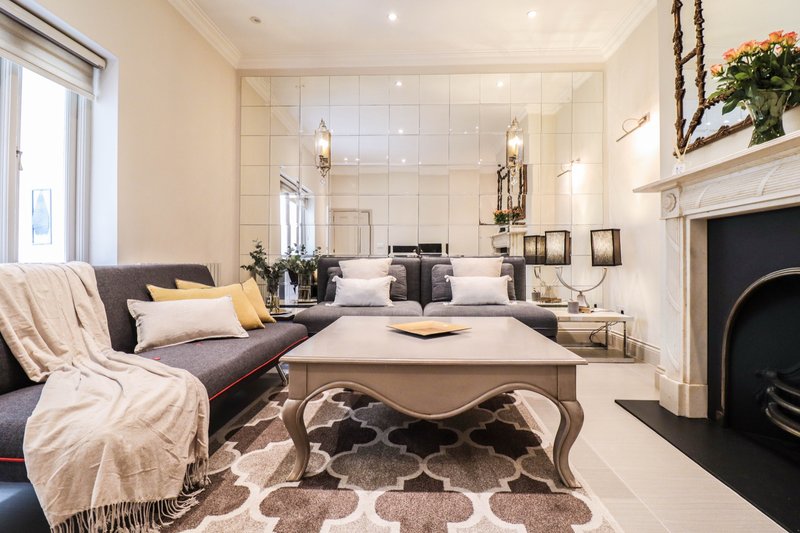 Luxury open-plan living room with grey sofa, fireplace, and marble bathroom visible through glass partition