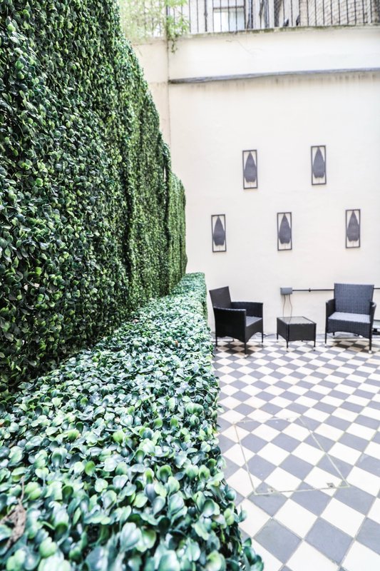 Outdoor courtyard with ivy-covered wall, checkered floor, and modern black seating