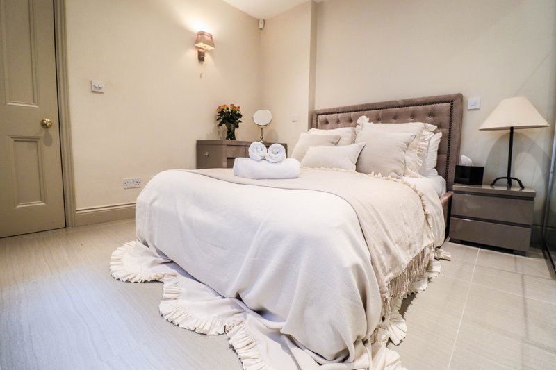 Bright modern bedroom with double bed, grey upholstered headboard, wooden nightstands, and soft lighting