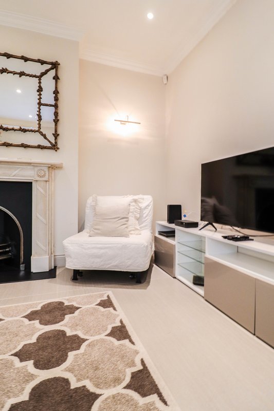 Modern living room with white armchair, TV unit, fireplace and patterned rug