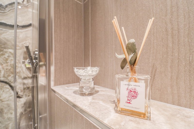 Bathroom shelf with decorative glass bowl, reed diffuser and shower enclosure