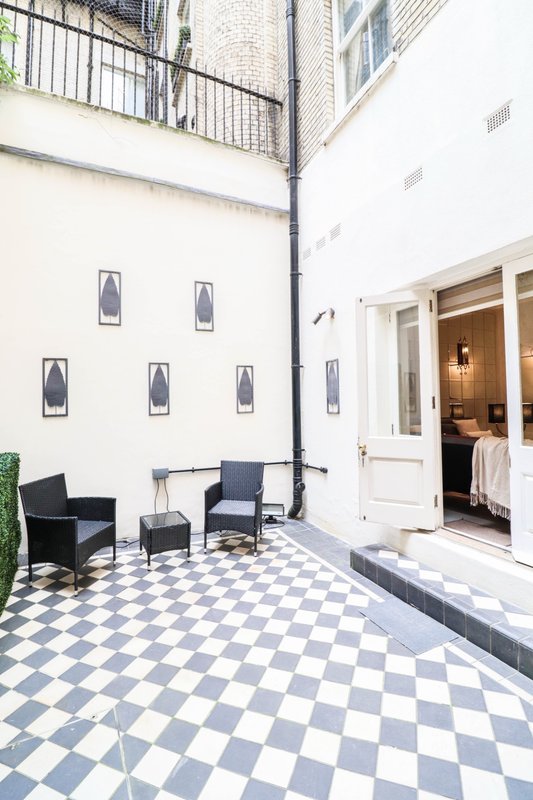 Outdoor courtyard with black and white checkered floor, seating area, and white building facade
