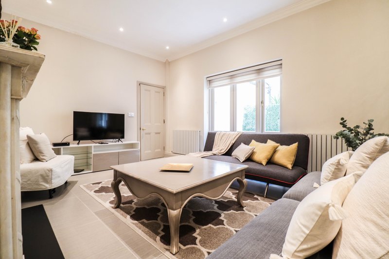Bright living room with cream sofa, dark couch, wooden coffee table and wall-mounted TV
