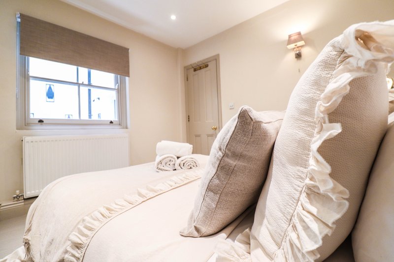 Bright bedroom with double bed, decorative pillows, window with blind and radiator