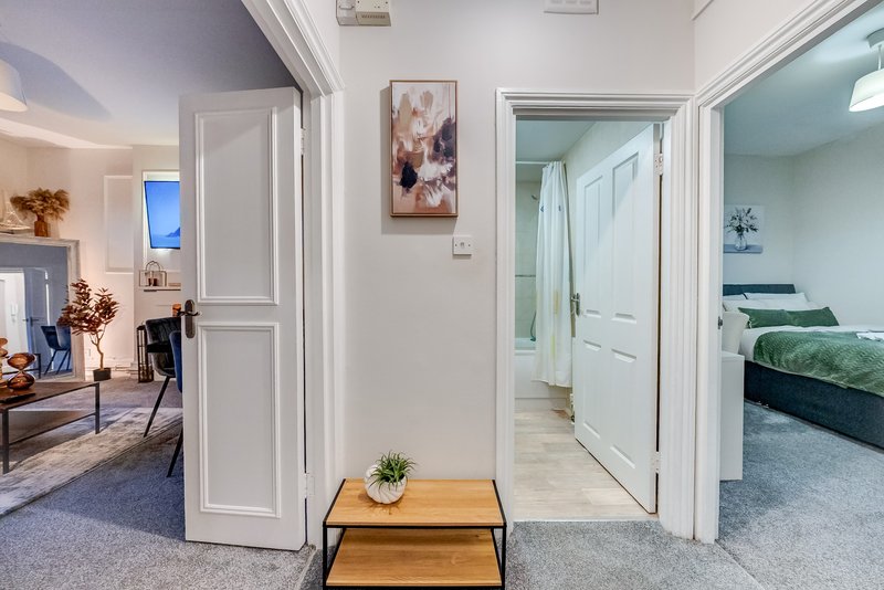 Bright hallway with wooden console table, multiple white doors opening to bedroom and living areas