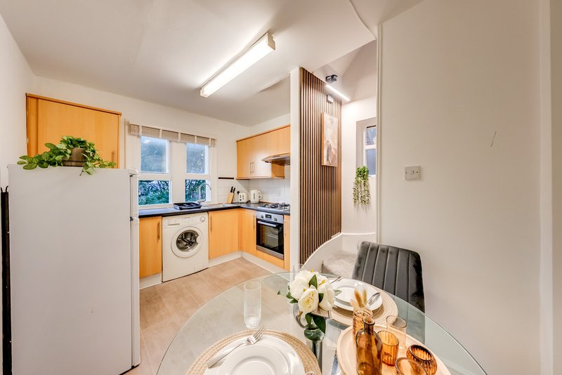 Modern kitchen with orange cabinets, washing machine, oven and dining area with flowers