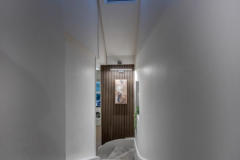 Narrow hallway with white walls, wooden door frame, and small potted plant