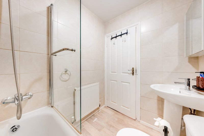 Modern bathroom with walk-in shower, white sink, toilet, and tiled walls