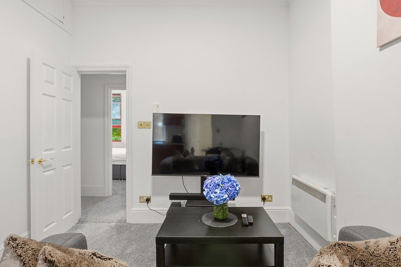 Modern living room with wall-mounted TV, black coffee table, and comfortable seating